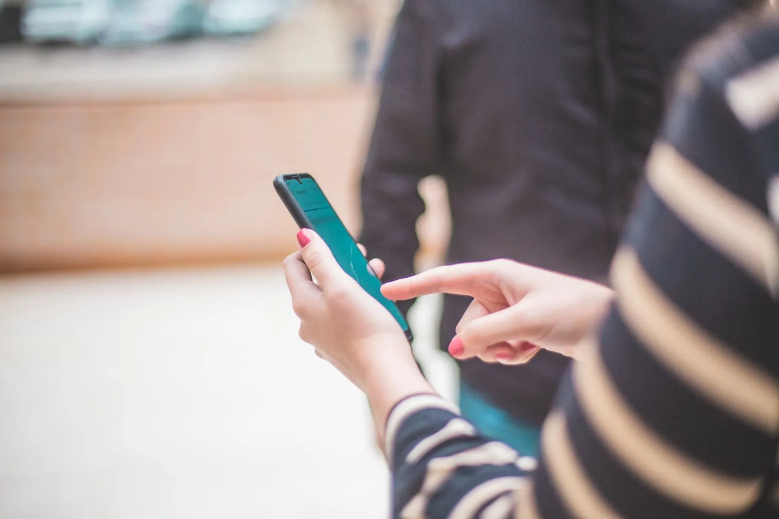Over-the-shoulder view of a person in a striped top using a smartphone.