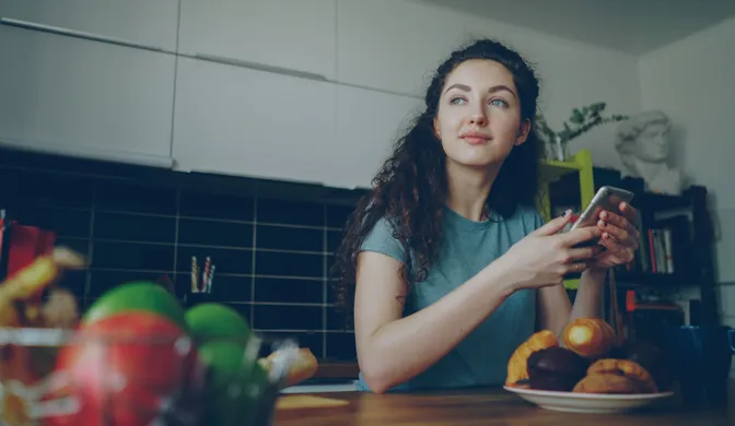 Young woman holding her phone at home